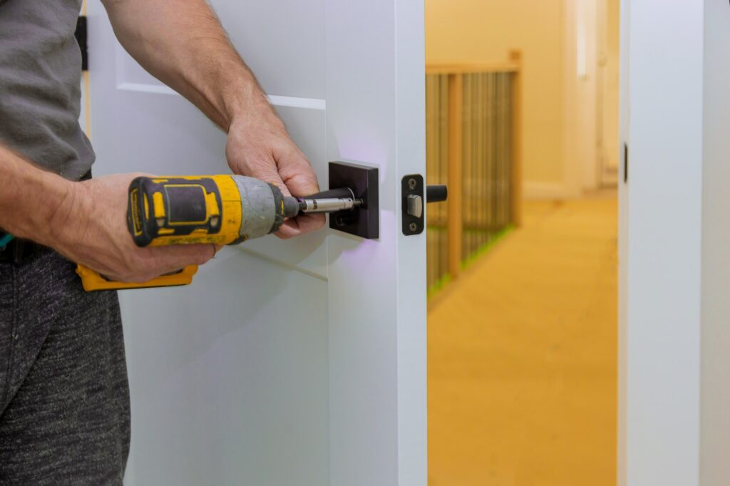 Handyman installing the door lock in the room with screwdriver